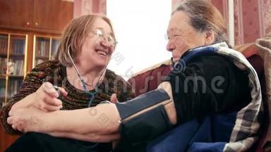 两个养老金领取者-高级女士享受乐趣-用压力计检查健康状况-测量压力，养老金领取者。